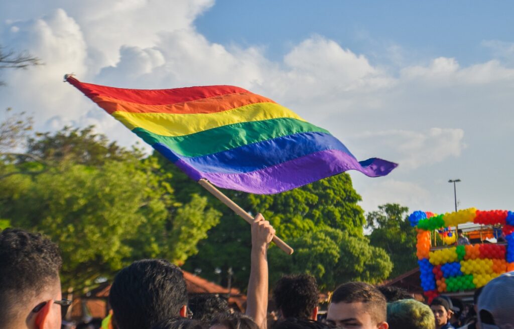 Bandeira LGBTQIA+ hasteada durante ato p&uacute;blico.