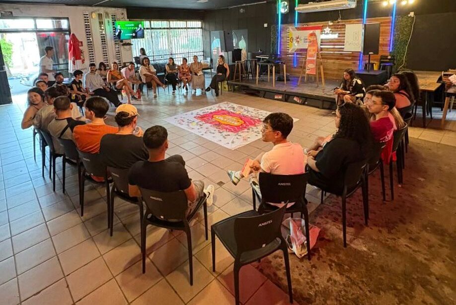 Participantes sentados em c&iacute;rculo durante o Date coletivo organizado pelo Comit&ecirc; de G&ecirc;nero e Sexualidade.